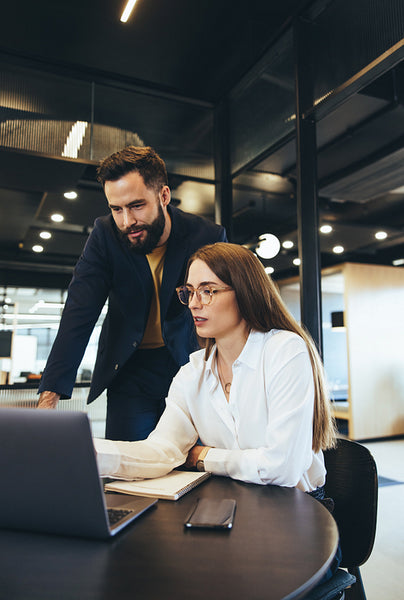 Coworkers using a laptop together in an office