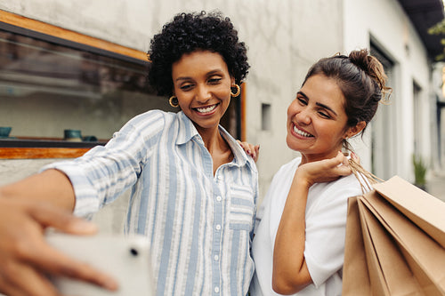 Happy young women taking a selfie after shopping in the city