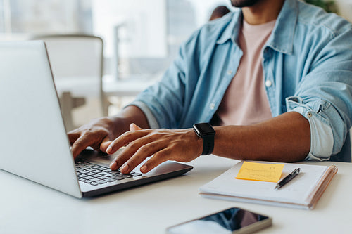 Anonymous businessman typing on laptop in modern office