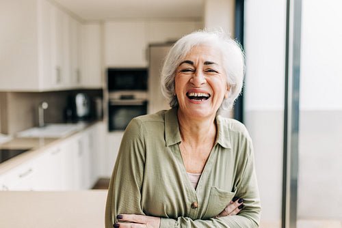 Cheerful elderly woman laughing happily inside her home