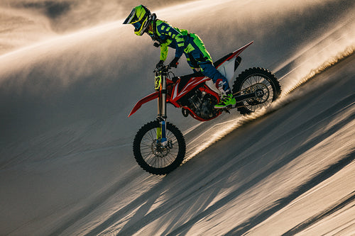 Professional motocross biker riding in sand dunes