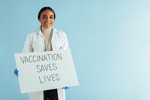 Medical doctor showing "Vaccination saves lives" banner
