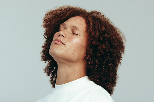Man with a curly afro and freckled face standing in a studio