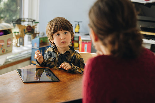 Kid drawing on digital tablet looking at his mother