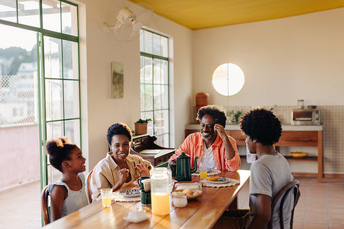 Happy Brazilian family sharing a morning meal of pão de queijo and coffee