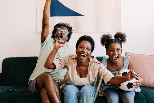 Excited family watching a football game together at home