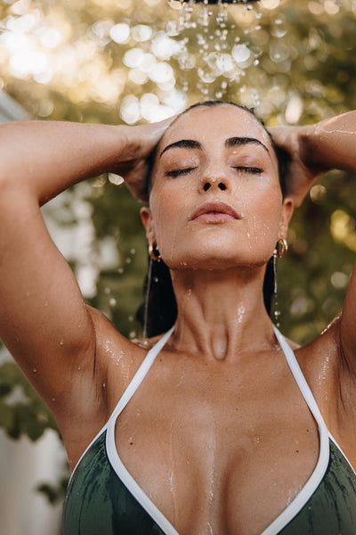 Luxurious young woman showering outdoors at a spa