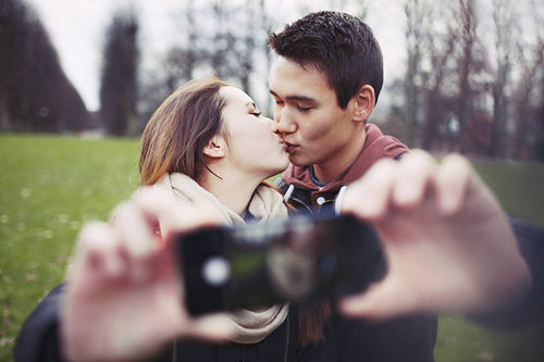 Lovely young couple taking self portrait while kissing