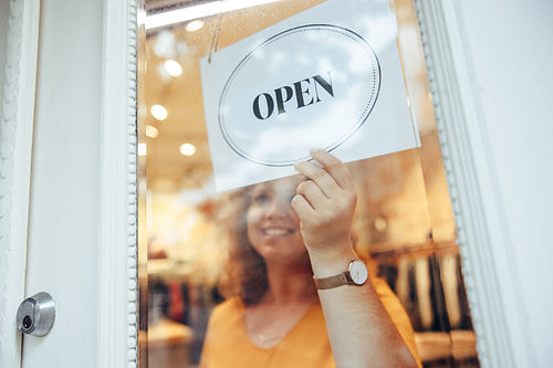 Woman hanging Open sign on her store door