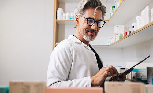 Mature pharmacist using a tablet in a clinic dispensary