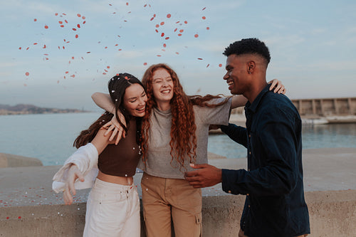 Loving friends embracing each other under falling confetti