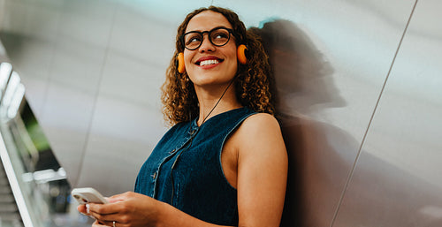 Commuting woman enjoys music with headphones in urban station