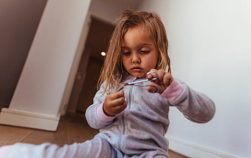 Girl cutting her own hair with scissors