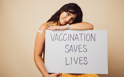 Attractive female with "vaccination saves lives" banner