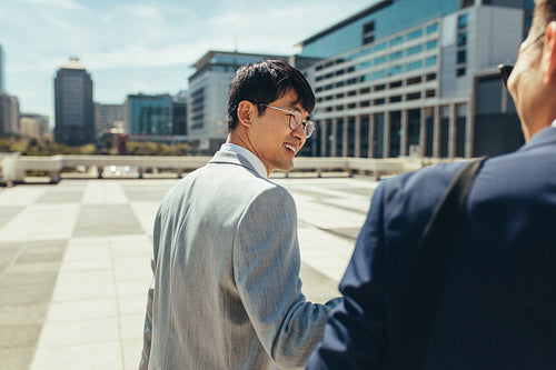Asian businessmen walking and talking in the city