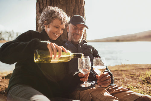 Senior couple enjoying drinks at campsite near Lake