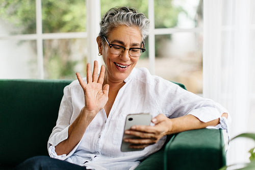 Senior woman waving on a video call as she connects with friends and family at home