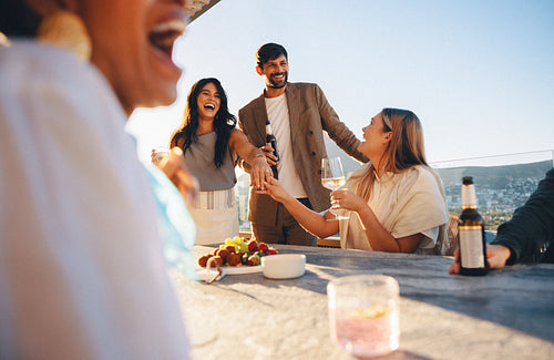 Friends enjoying a rooftop gathering with cocktails and laughter