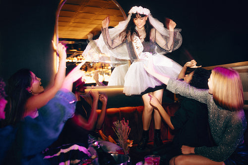Woman celebrating her bachelorette party surrounded by friends in a festive setting