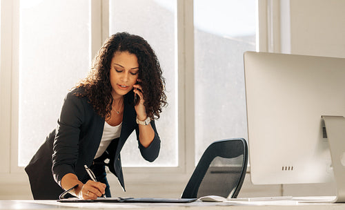 Businesswoman writing notes standing at her desk