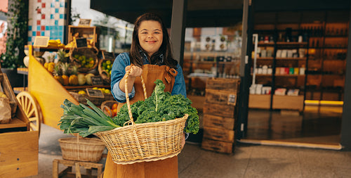 Shop employee with Down syndrome holding a basket of fresh organic vegetables