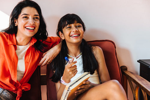 Smiling Latino mother and daughter enjoying quality time together indoors
