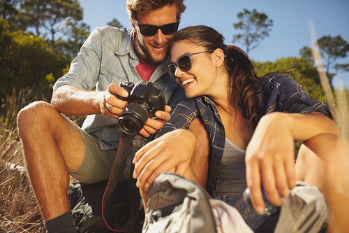 Smiling couple on a hike looking pictures on digital camera
