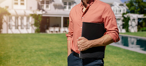 Real estate agent standing outside a house for sale