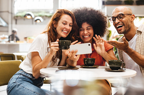 Group of friends making a video call during a social gathering in a coffee shop