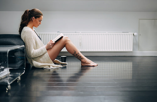 Pretty lady on floor at home reading a novel