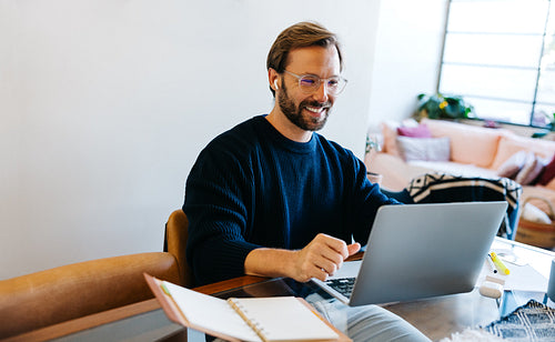 Man at home working on laptop with smile