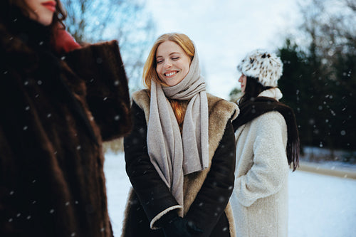 Smiling ginger woman with friends in winter snow