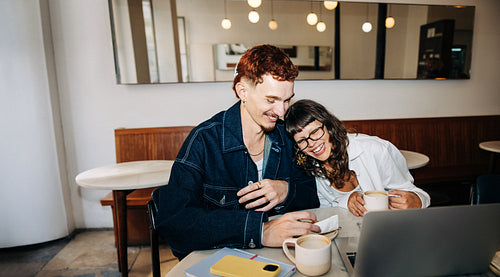 Couple sharing coffee and laptop at cafe