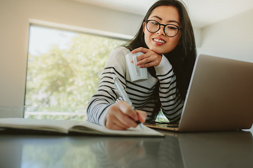 Woman studying at home with laptop on table
