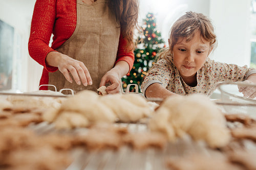 Little girl helping her mother in making cookies for  Christmas.