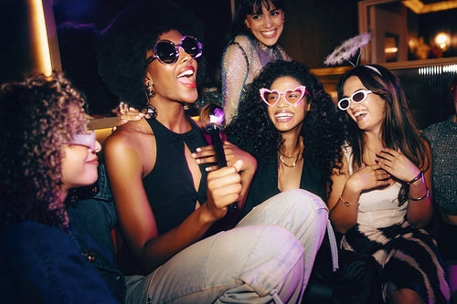 Happy women singing and laughing together during a lively nighttime celebration