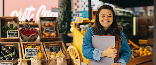 Happy shopkeeper with Down syndrome standing in a grocery store