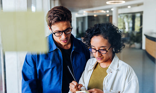 Two professionals review notes in a hallway