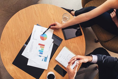 Two business people working with charts around table