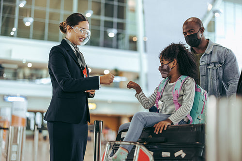 Airport attendant greeting small girl with family