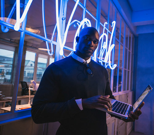 Young executive standing in office with a laptop