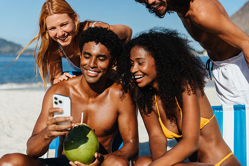 Friends on vacation in vibrant swimwear while capturing fun moments on a smartphone
