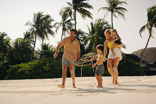 Family walking to the ocean carrying reef restoration frame