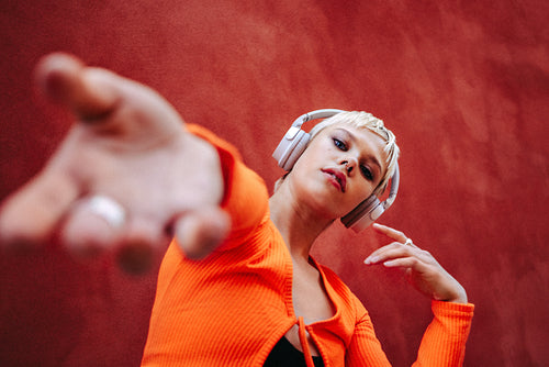 Woman listens to music on headphones in a studio portrait against a red background