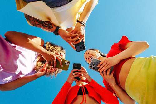 Friends share smartphone interaction outdoors in a sunny circle