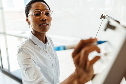 Professional woman writing on a whiteboard in a modern office setting