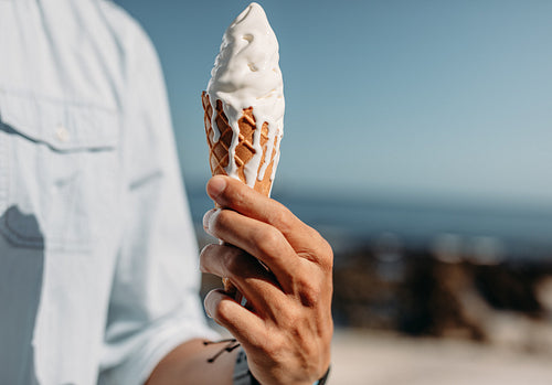 Close up of a man holding a cone ice cream