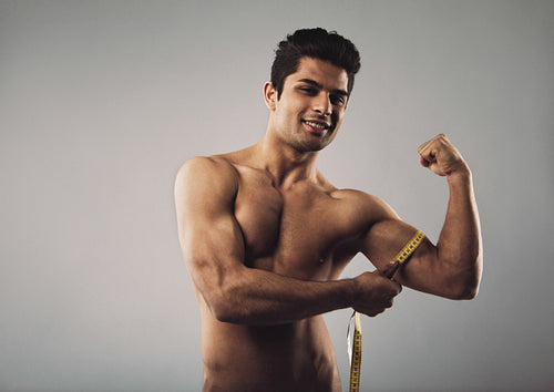 Man measuring his biceps with a tape measure