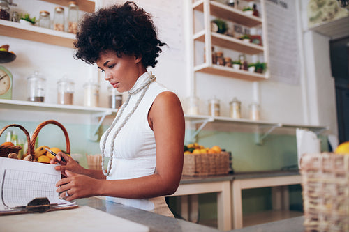 Young african woman doing accounts in juice bar