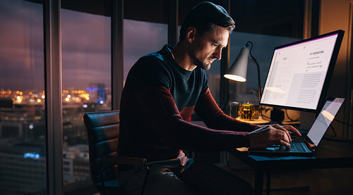 Overtime work: Dedicated business professional typing on his laptop at night
